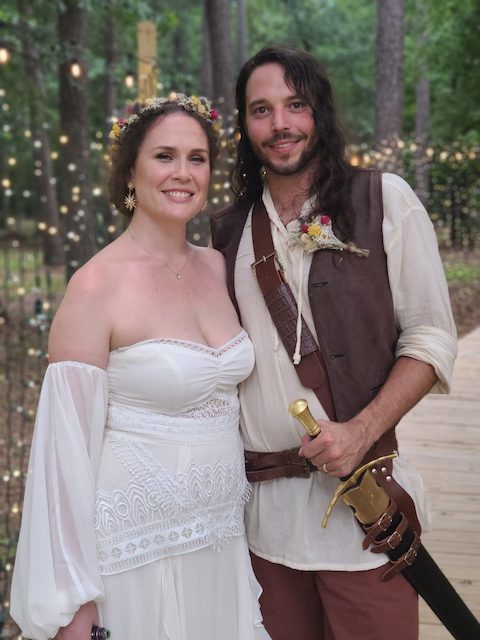 A man and woman dressed in medieval costumes pose for a photo at a Texas wedding venue.