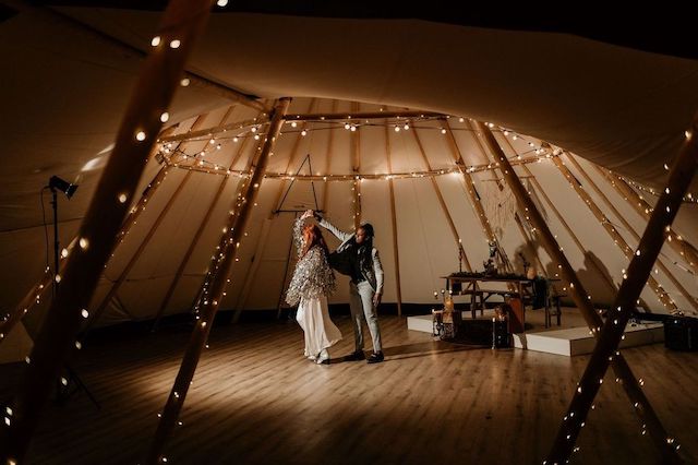 A couple standing inside a beautifully lit tepee at one of the best wedding venues in Houston, Texas.