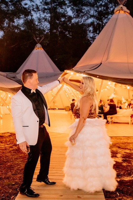A bride and groom dancing in front of a teepee tent at a wedding venue in Houston, Texas.