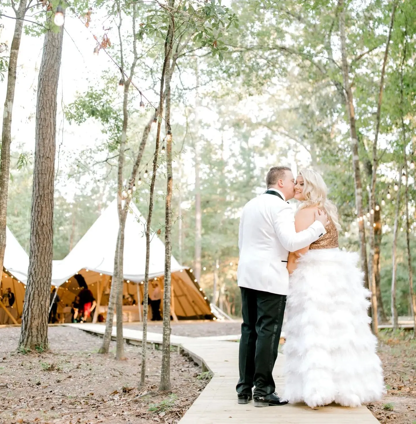 Bride and groom golden-hour portrait among pine trees with tipi backdrop and soft forest landscape at The Shire Tipis, Huntsville, TX